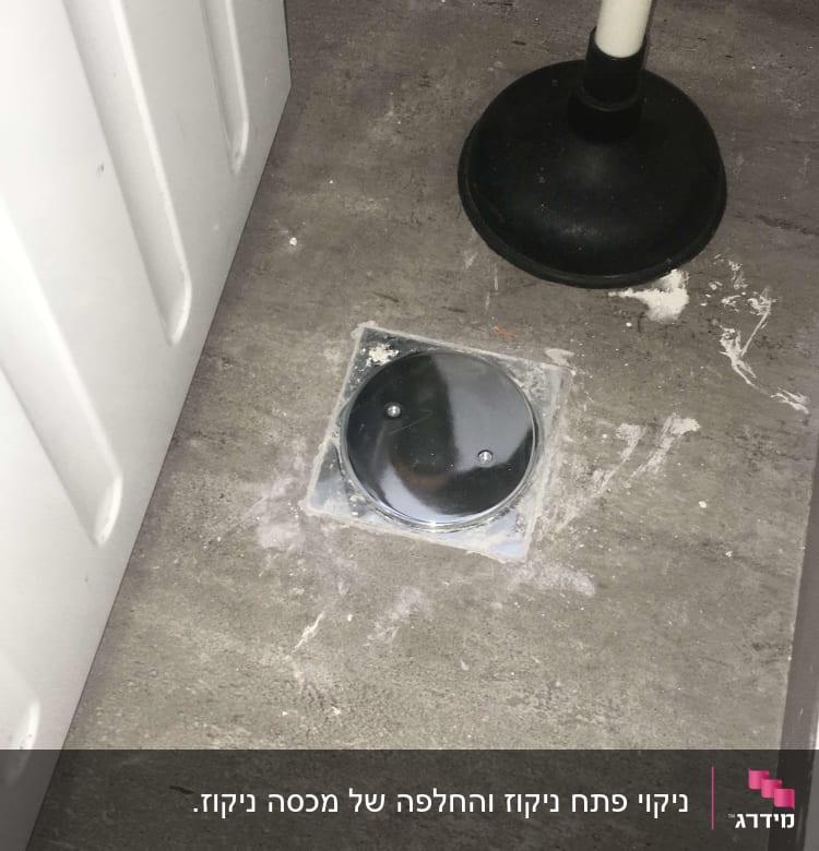 פומפה שחורה על רצפה ליד מכסה ניקוז מתכת